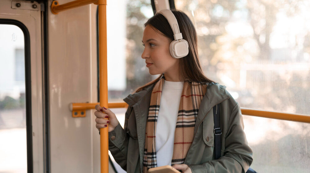 Chica yendo al trabajo en autobús con cascos de música sonriendo