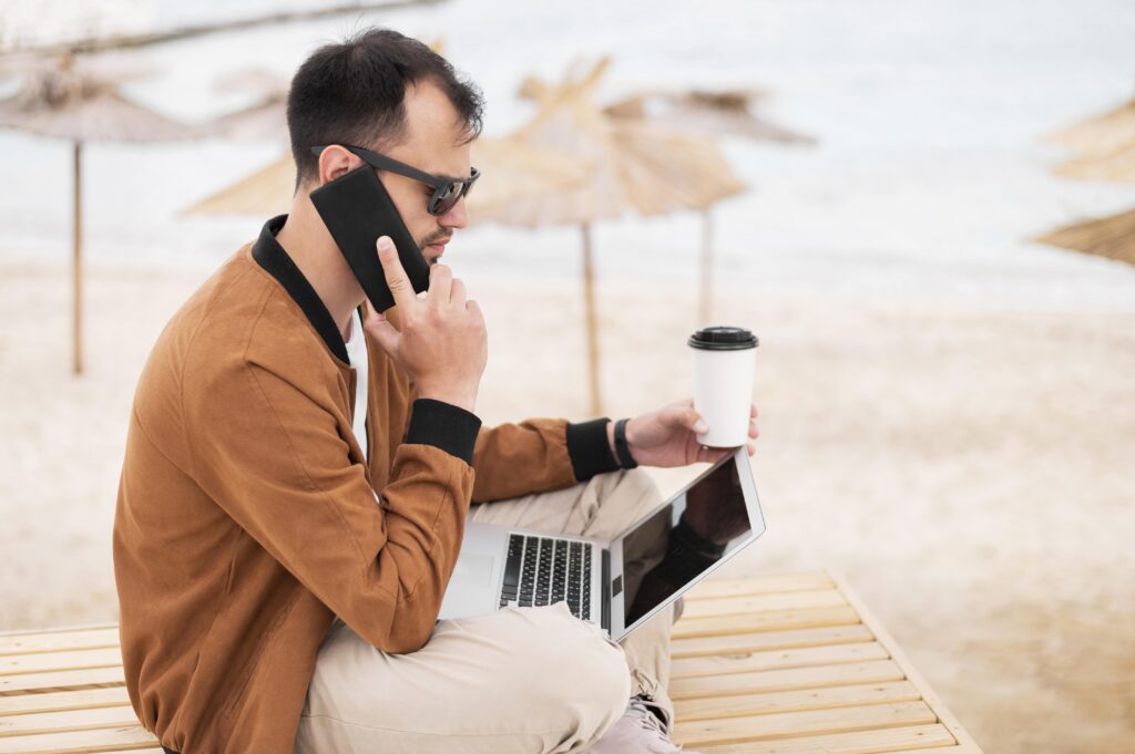 Señor preocupado sentado con un portátil, hablando por teléfono y con un café
