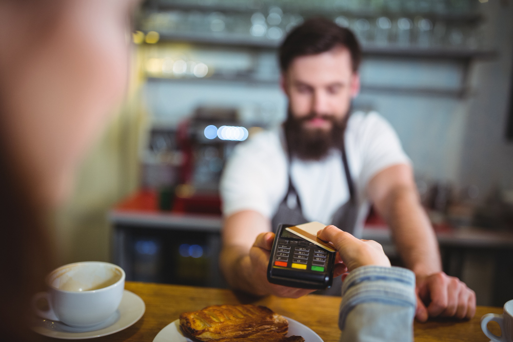 Persona pagando un desayuno en un bar con tarjeta