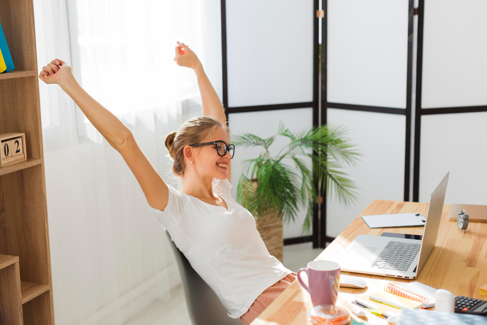 Mujer sentada en un escritorio feliz y relajada tras su vuelta al trabajo después de vacaciones