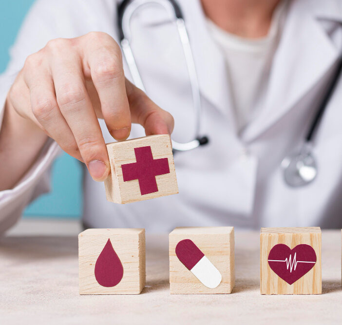Médico sobre un escritorio con un cubo con una cruz que representa un sello de salud en la mano.