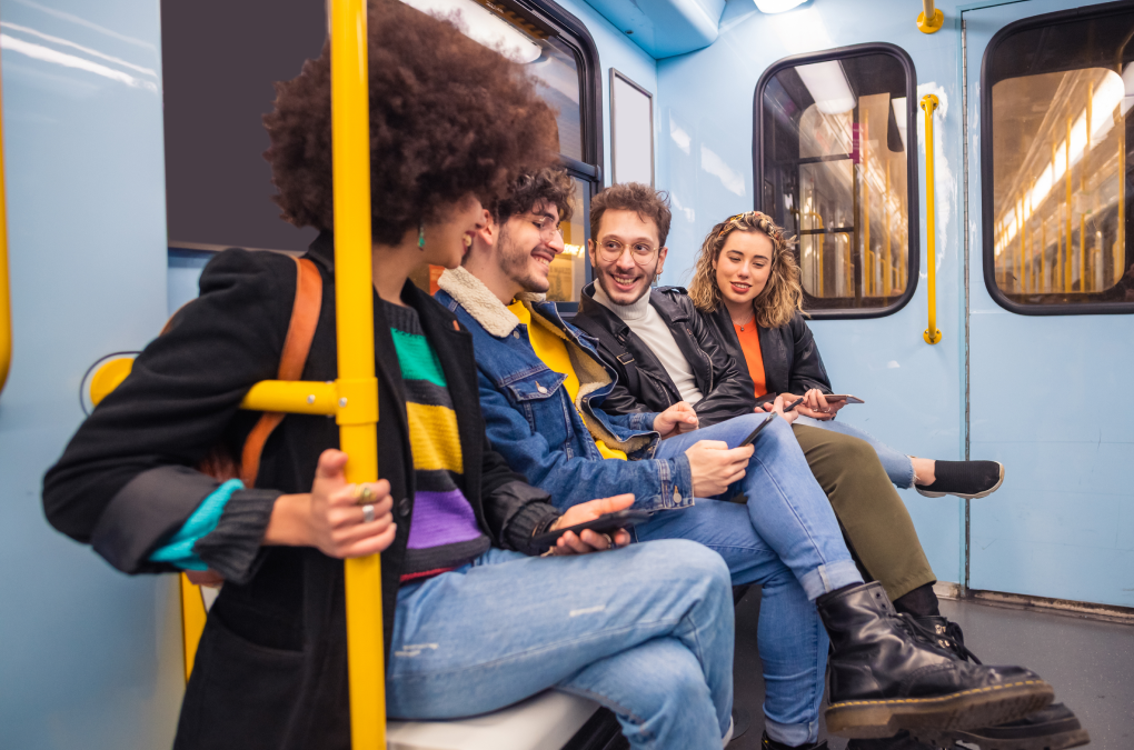 UN GRUPO DE CHICOS JÓVENES SENTADOS EN EL METRO RIENDO Y HABLANDO