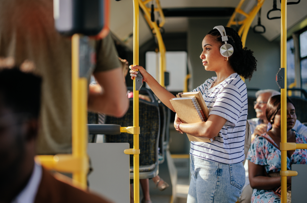 una chica en el autobús, de pie y mirando por la ventana
