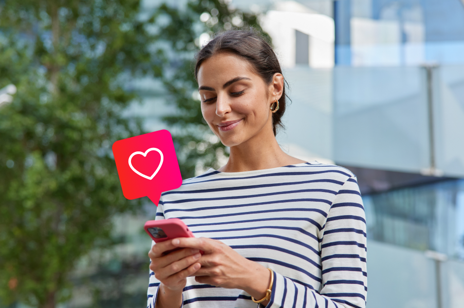 Mujer consultando smartphone al aire libre con icono de corazón