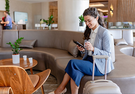 Mujer profesional con equipaje usando smartphone en sala de espera