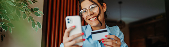 Mujer alegre realizando compra online con tarjeta y smartphone