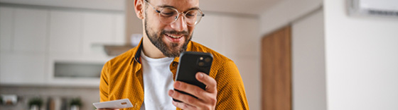 Hombre sonriente usando smartphone en casa
