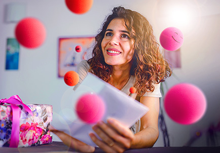 Mujer sonriente sosteniendo un sobre y con un regalo sobre la mesa