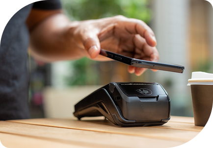 Persona realizando pago contactless con smartphone en datáfono en comercio