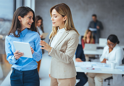 Dos profesionales conversando con tablet en ambiente de oficina corporativa