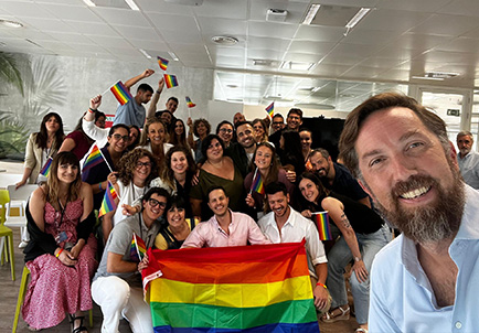 Empleados de Edenred celebrando diversidad e inclusión con bandera arcoíris en oficina