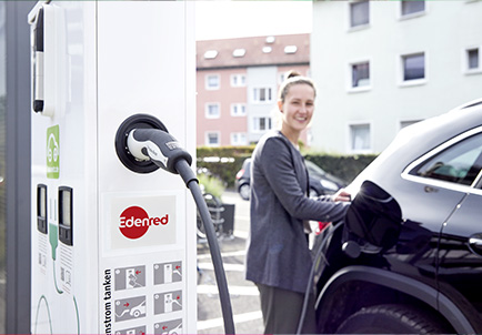 Mujer cargando vehículo eléctrico en punto de recarga Edenred para sostenibilidad