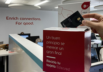 Mano introduciendo una tarjeta Edenred en una caja de reciclaje