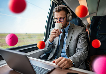 Ejecutivo trabajando con laptop mientras toma café en tren
