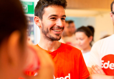 Empleado sonriente de Edenred en camiseta roja en ambiente de trabajo