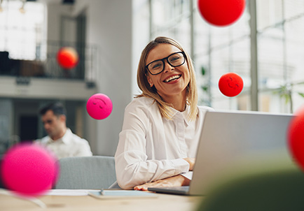 Mujer sonriente con gafas trabajando en laptop en oficina luminosa