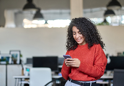 Mujer sonriente usando smartphone en oficina moderna