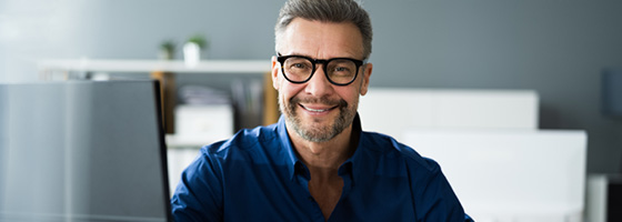 Man with glasses smiling at camera in office