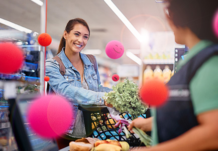 Cliente sonriente comprando verduras en supermercado con datáfono de pago