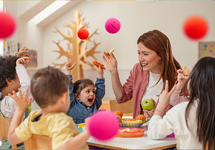 Grupo de niños jugando con pelotas de colores junto a educadoras en actividad recreativa en guardería