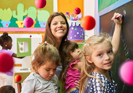 Educadora infantil sonriente con tres niños en una guardería colorida y decorada