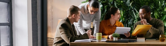 Equipo de trabajo colaborando en proyecto con laptops y documentos en oficina