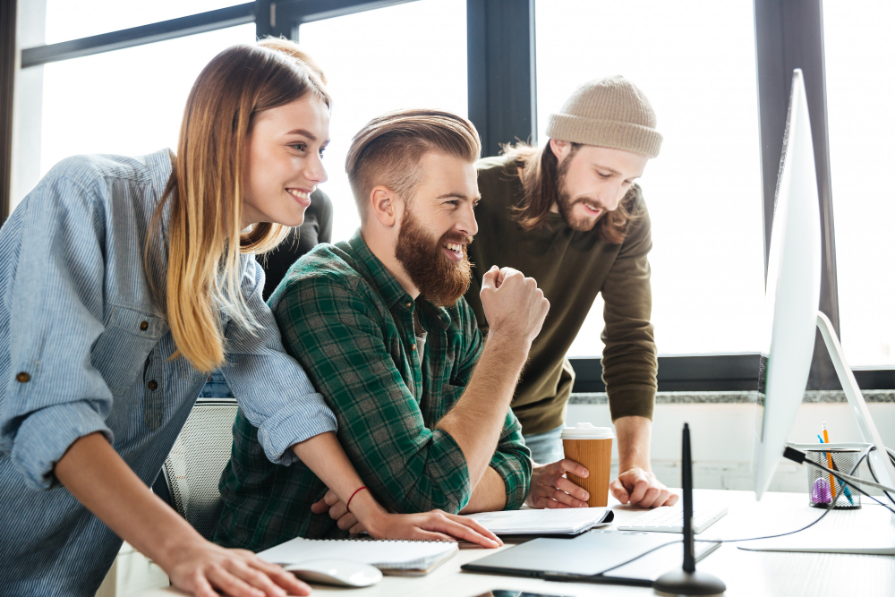 Tres compañeros de trabajo colaboran frente a un ordenador en una oficina moderna