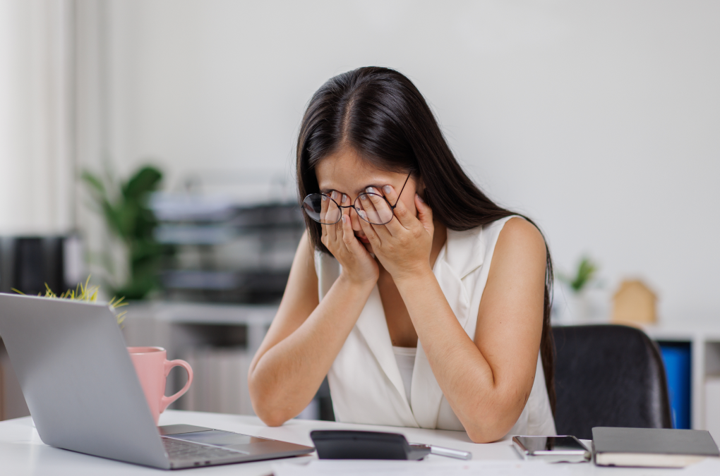 una chica en la oficina cansada delante del ordenador, frotándose los ojos