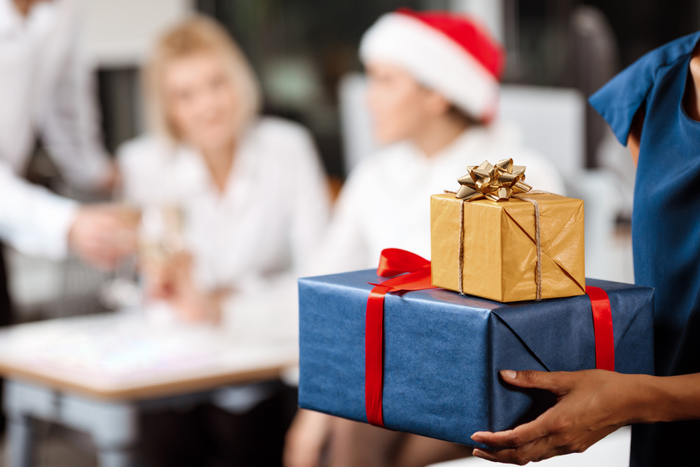 Regalos de Navidad para empleados: cajas de regalo envueltas en azul y dorado con lazos rojos.